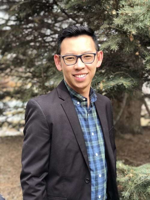 Rendy Marican, Kaiser therapist, stands in front of a tree wearing a blue shirt and blazer in Denver, Colorado.